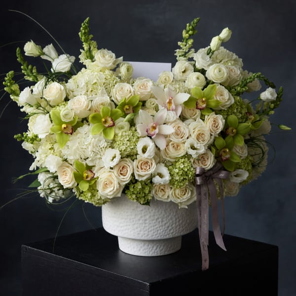 Large white and cream floral arrangement in a textured white vase