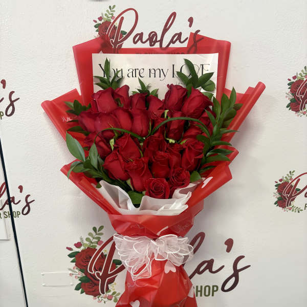 Bouquet of red roses wrapped in red paper with a white bow