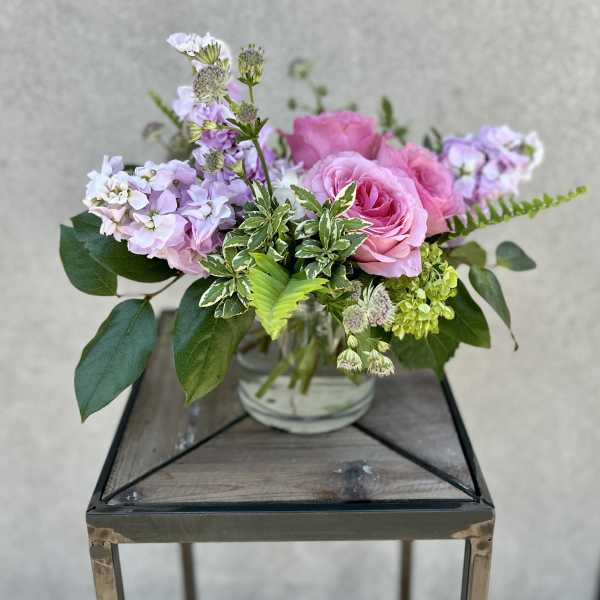Pink roses and lavender flowers arranged in a glass vase
