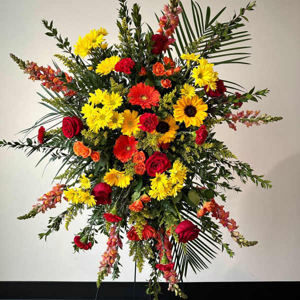 Tall standing floral spray with red, yellow, and orange blooms