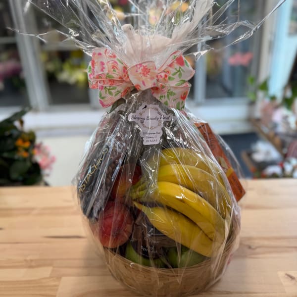 Gift basket with fruit and packaged snacks wrapped in cellophane and a floral bow