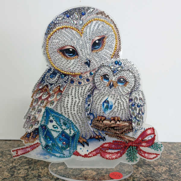 Jeweled owl and owlet figurine with blue gem cube and red beaded bow on a clear stand