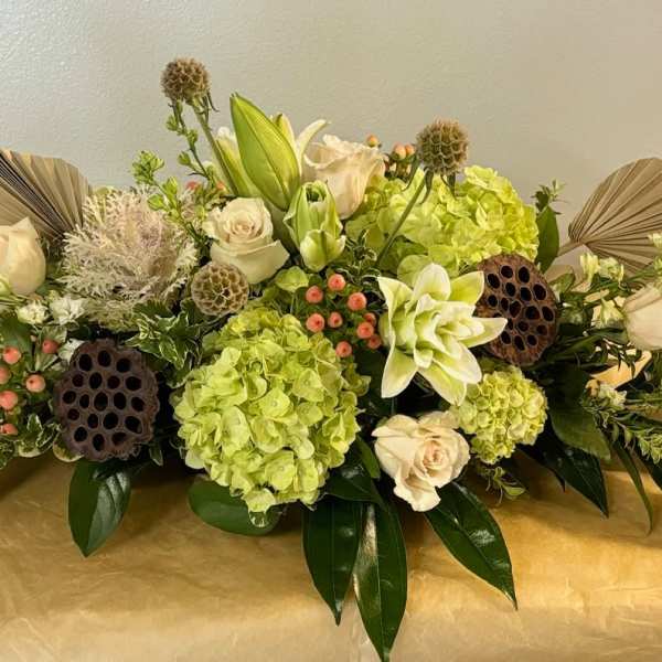 Low floral centerpiece with cream roses, green hydrangeas, and lilies