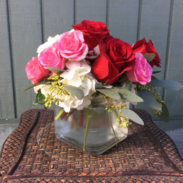 Pink and red roses arranged in a clear glass vase