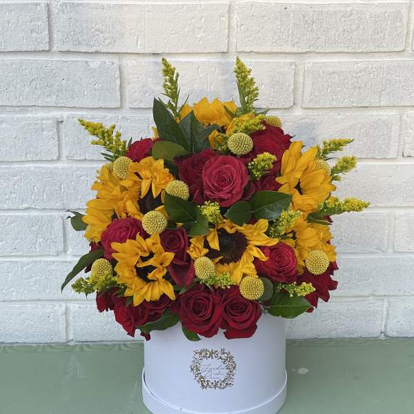 Red roses and yellow sunflowers in a white hat box