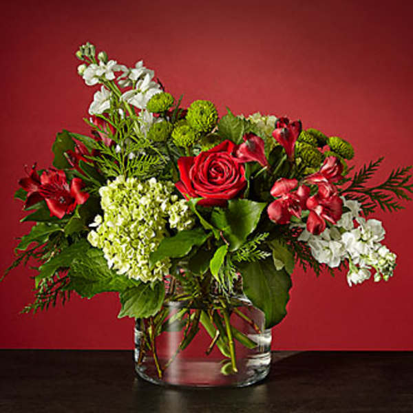 Red roses and white flowers arranged in a clear glass vase