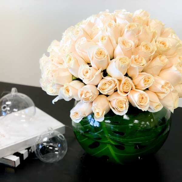 Bouquet of pale peach roses in a green glass vase