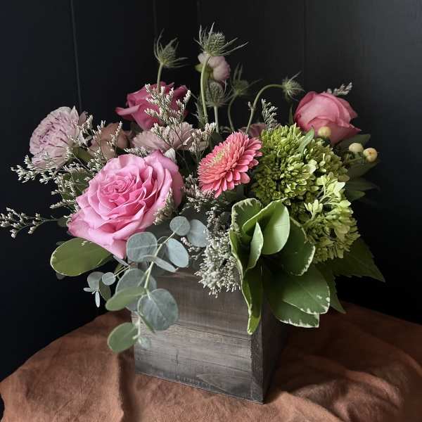 Pink roses and mixed blooms arranged in a wooden box