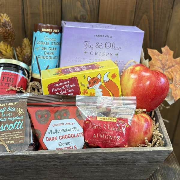 Gift basket with apples, snacks, tea, and autumn leaves