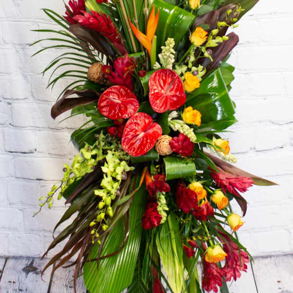 Tall tropical floral spray with red and yellow blooms on a stand