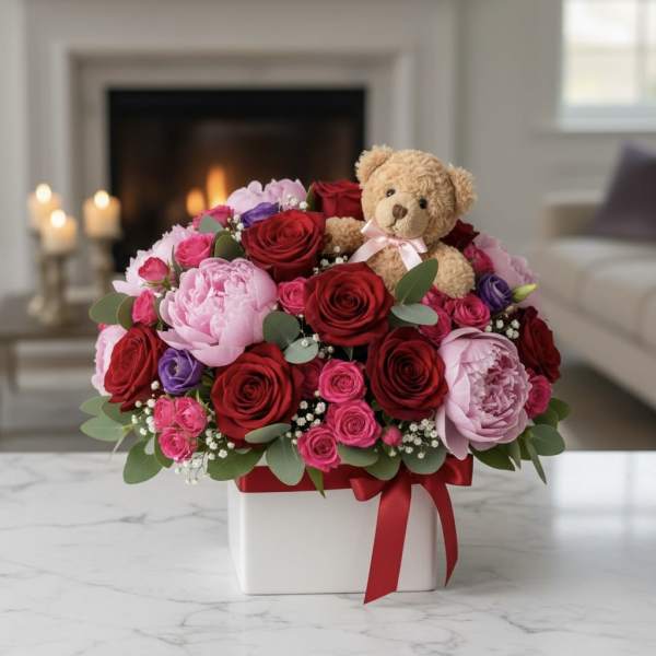 Bouquet of red, pink, and purple roses with a teddy bear in a white box