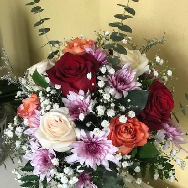 Bouquet of roses and purple daisies in a clear glass vase