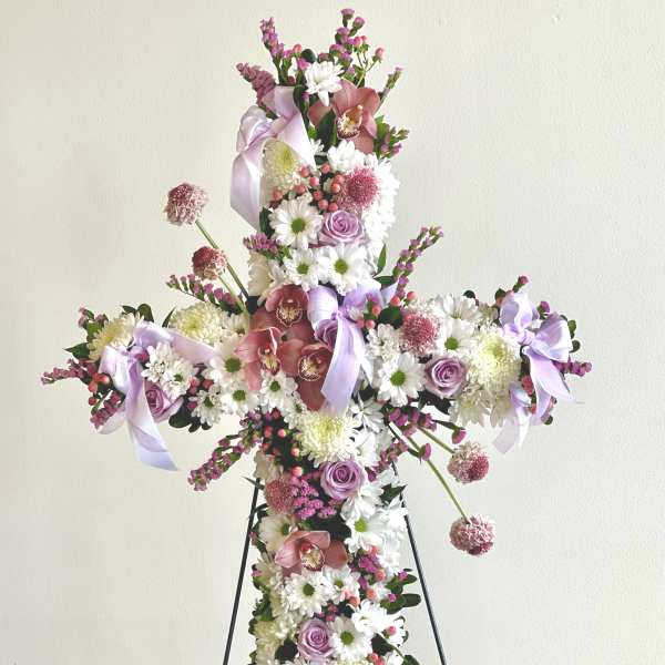 Cross-shaped floral arrangement with pink and white flowers on a stand