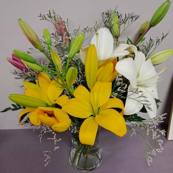 Bouquet of yellow and white lilies in a clear glass vase