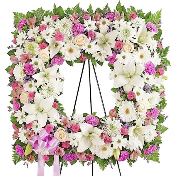Large floral wreath on a black stand with white lilies, daisies, and pink blooms