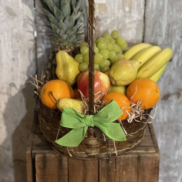 Basket of assorted fruit with a pineapple and green ribbon