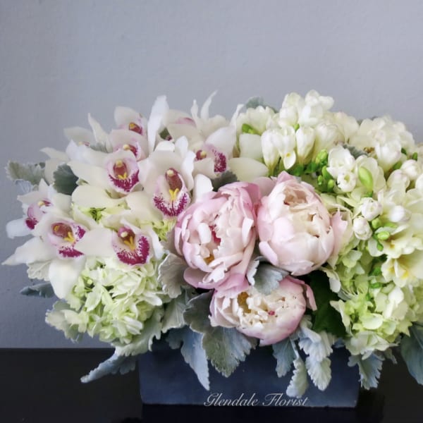 Pink peonies and white orchids in a dark box arrangement
