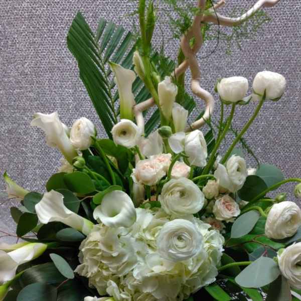White floral arrangement with calla lilies, ranunculus, and hydrangea