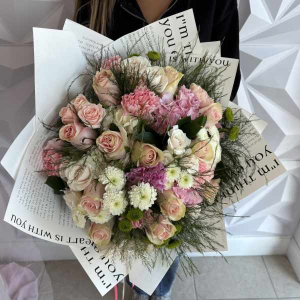 Bouquet of pink and white roses with mixed blooms wrapped in printed paper