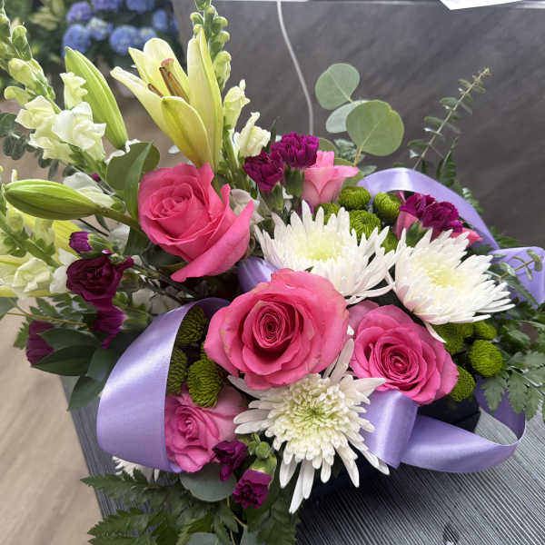 Bouquet of pink roses, white lilies, and white chrysanthemums with a lavender ribbon