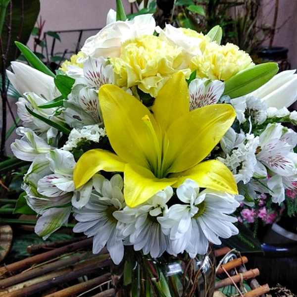 Yellow lily bouquet with white daisies in a glass vase