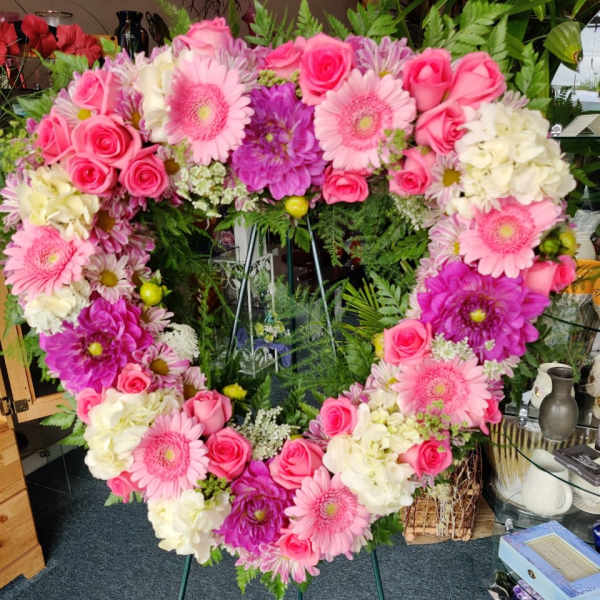Heart-shaped floral wreath with pink roses, gerbera daisies, and white blooms