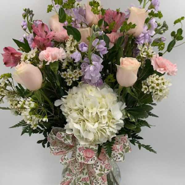 Mixed pink and lavender bouquet in a glass vase with a floral ribbon