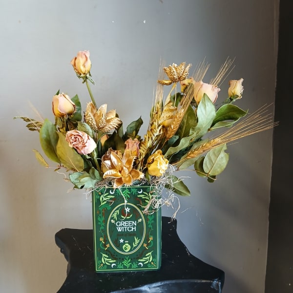 Pink roses and dried gold accents arranged in a green decorative box
