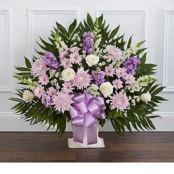 Lavender and white floral spray with a purple ribbon on a stand
