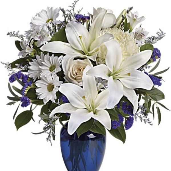 White lilies and daisies arranged in a blue vase