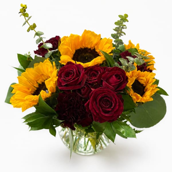 Bouquet of red roses and yellow sunflowers in a glass vase