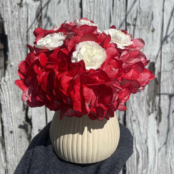 Red and white flower arrangement in a beige ribbed vase