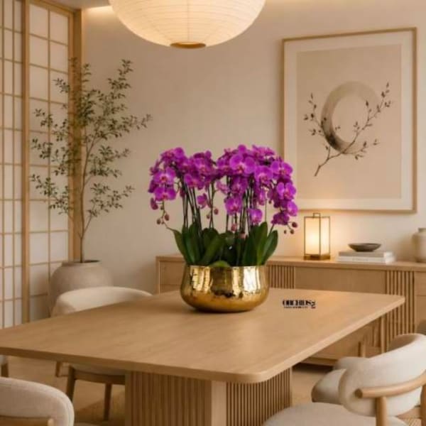 Purple orchids in a gold bowl on a wooden table