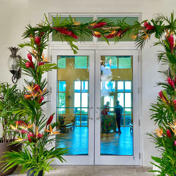 Tropical floral arch with pink and orange flowers framing double doors