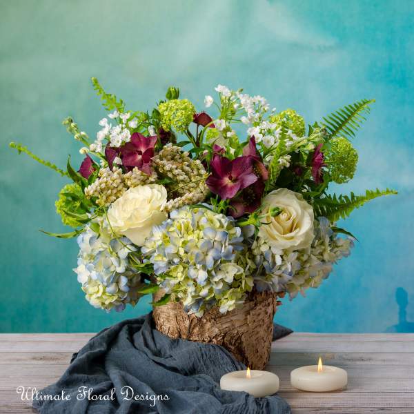 Floral arrangement in a birch bark container with candles in front