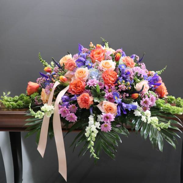 Large pastel floral spray with roses, carnations, and purple blooms