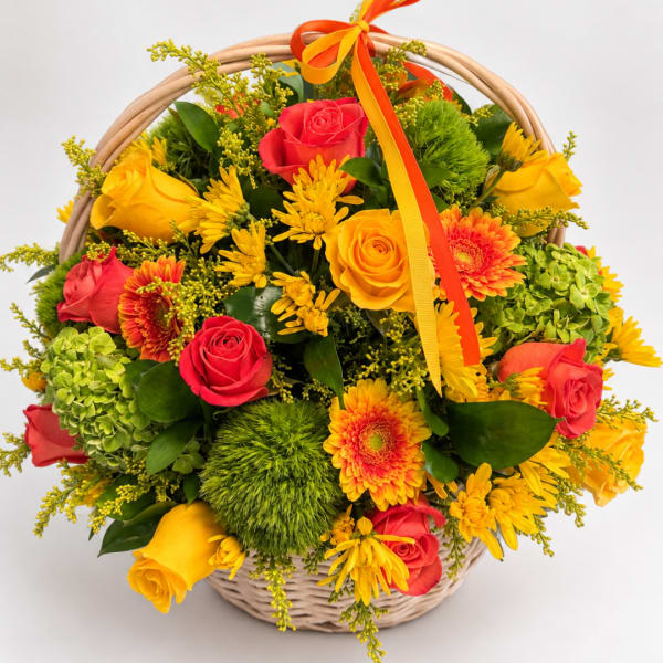 Basket of red and yellow roses with orange daisies and green pom-pom flowers