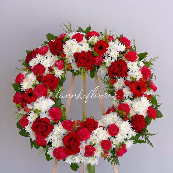 Red and white floral wreath on a wooden easel