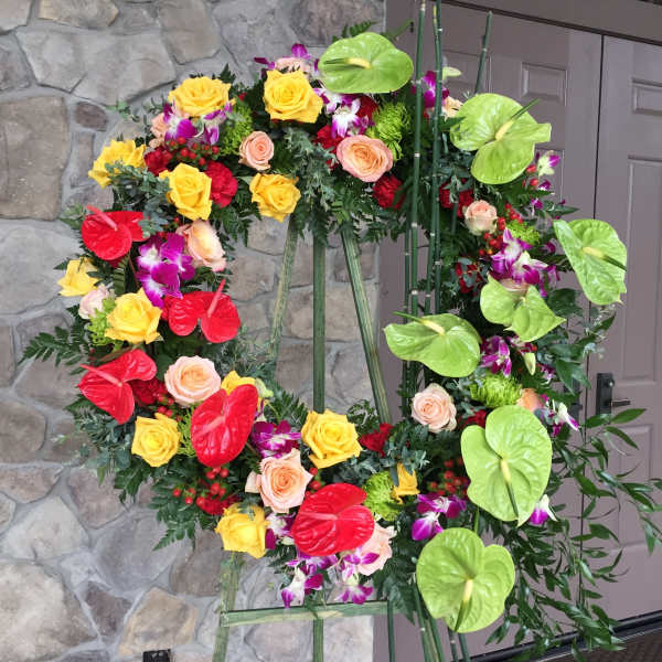 Heart-shaped floral wreath with roses and anthuriums on a stand