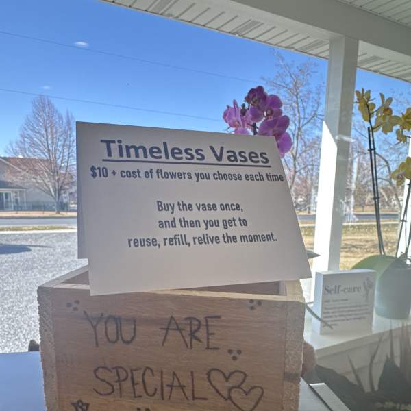 Store display sign for reusable vases with orchids in the background