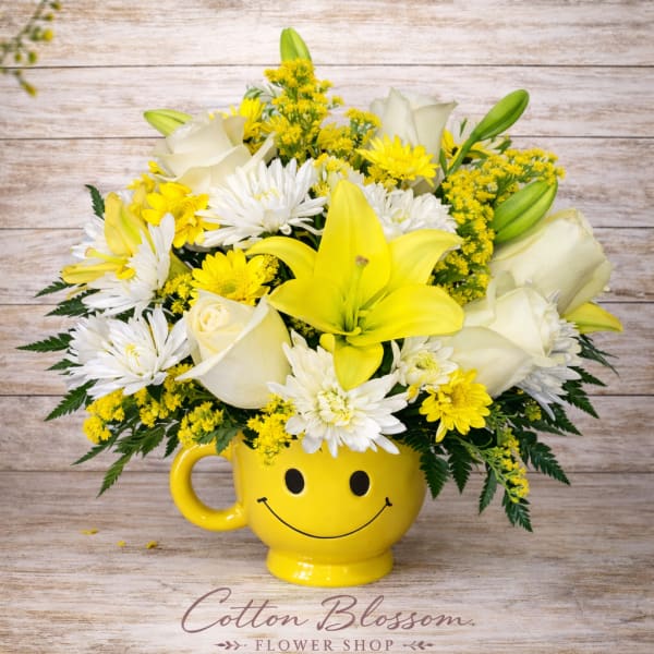 Yellow and white bouquet in a smiley-face mug vase