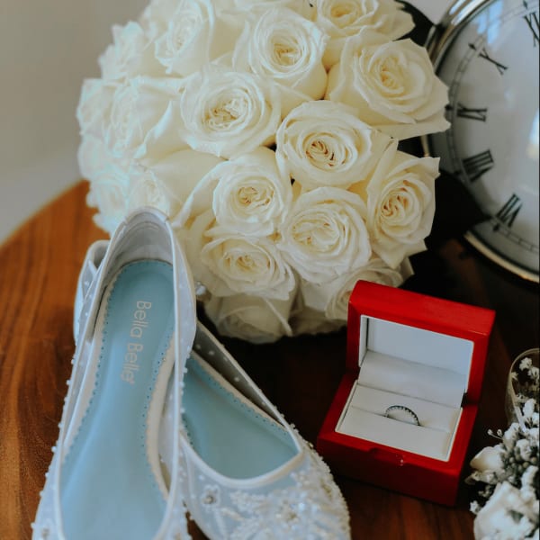 White rose bouquet with bridal shoes, ring box, and clock