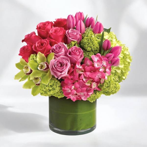 Pink roses and tulips arranged in a green glass vase