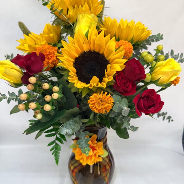 Sunflower and red rose bouquet in a dark glass vase