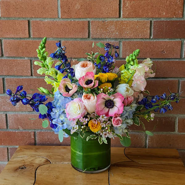 Colorful mixed flower arrangement in a green glass vase