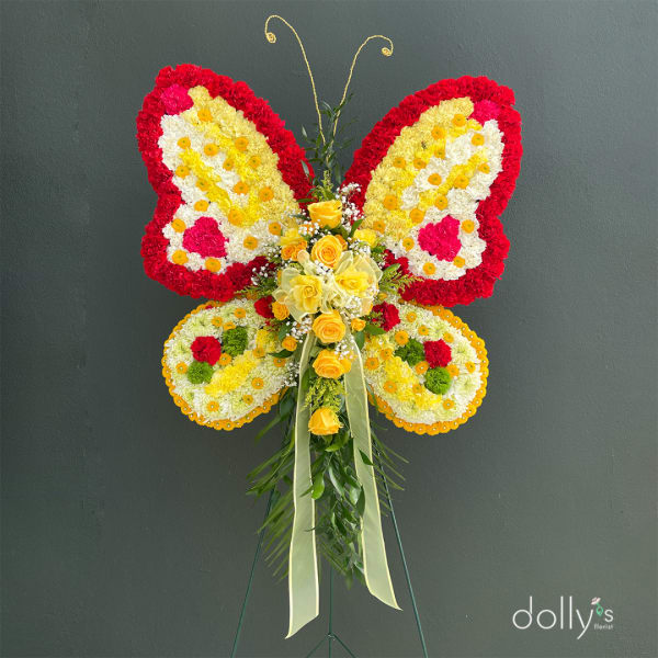 Butterfly-shaped floral standing arrangement with yellow roses and red, white, and yellow flowers