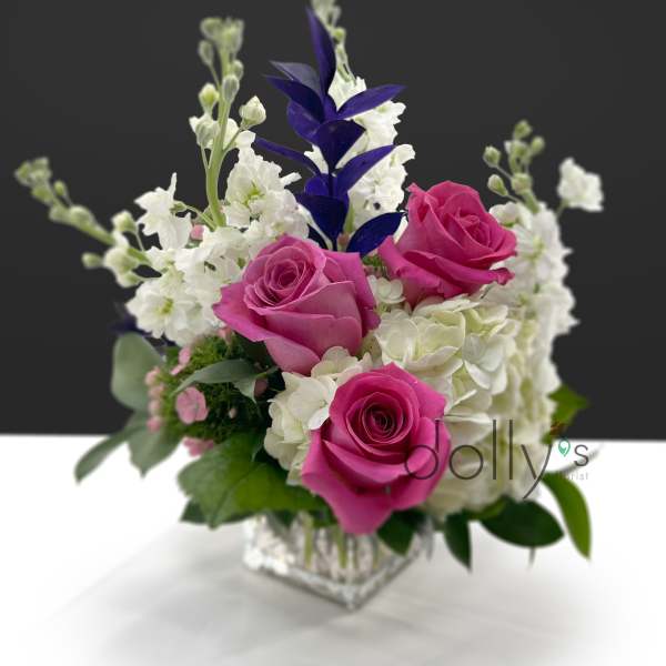Pink roses and white flowers arranged in a clear square vase