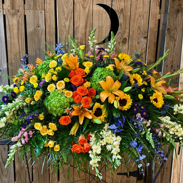 Large mixed floral arrangement with orange lilies, roses, and sunflowers