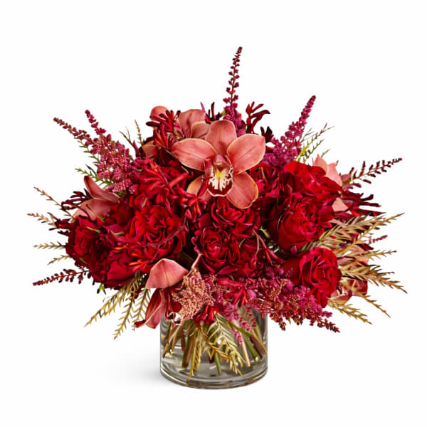 Red floral arrangement with orchids and roses in a glass vase