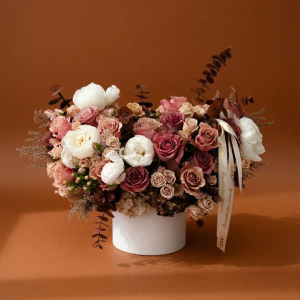 Pink and white rose arrangement in a white vase